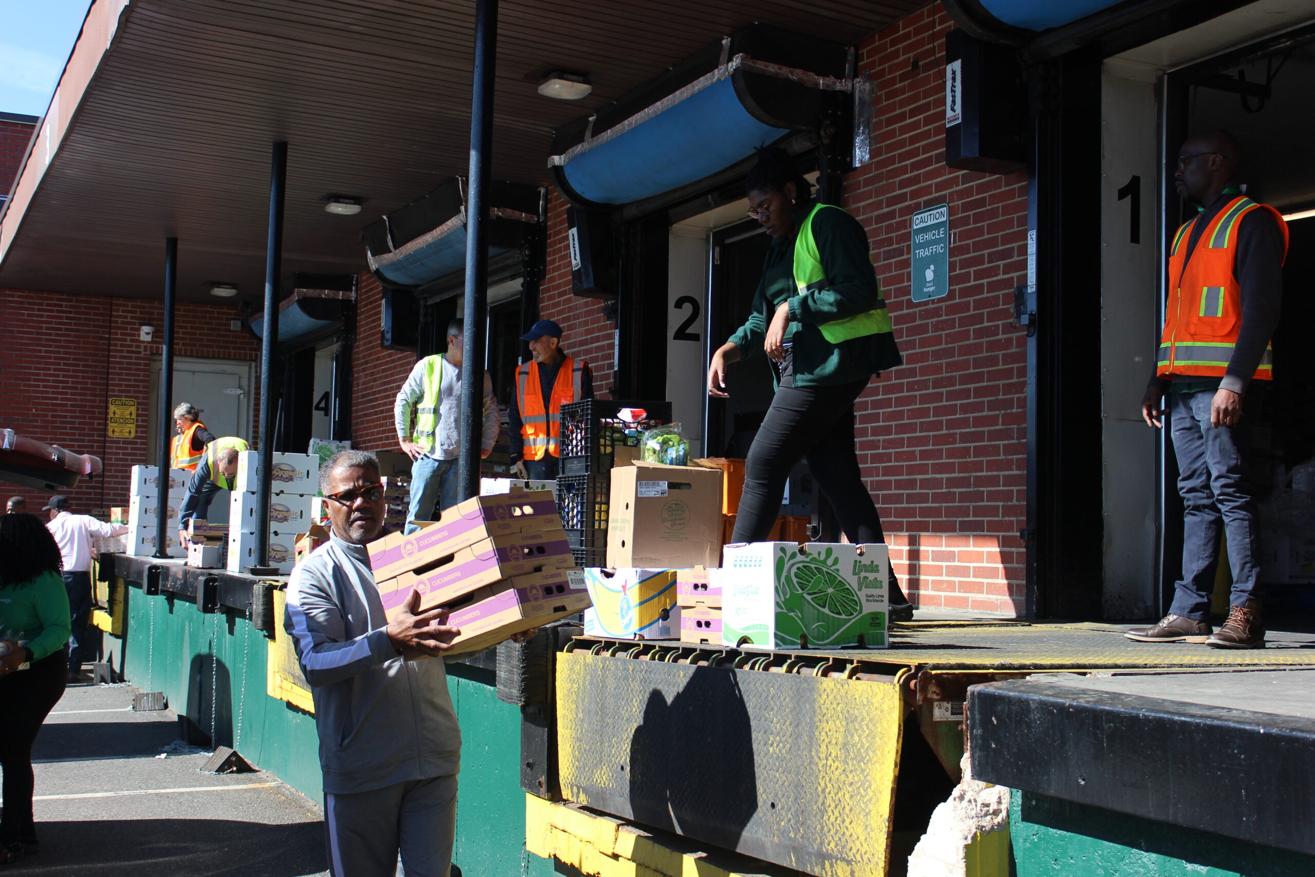 Volunteers organizing meal boxes in front of the warehouse loading dock outside | volunteer | food service